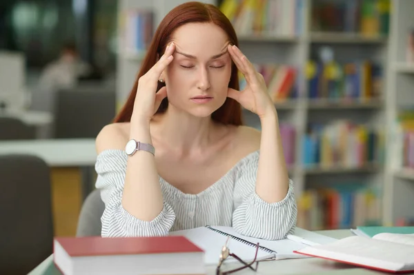 Uitgeputte jonge vrouwelijke geleerde met hoofdpijn — Stockfoto