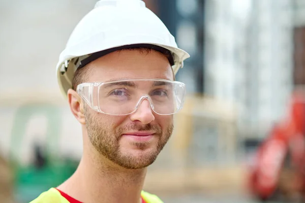 Agradable constructor atractivo en gafas de seguridad posando para la cámara —  Fotos de Stock