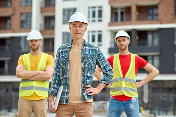 Drei Männer mit Schutzhelmen stehen auf der Baustelle — Stockfoto