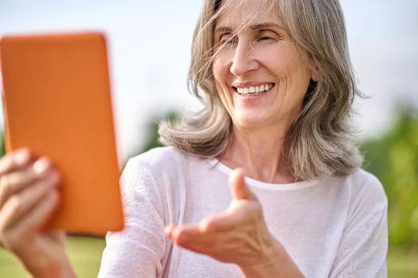 Lycklig vuxen kvinna med tablett i utsträckt hand — Stockfoto