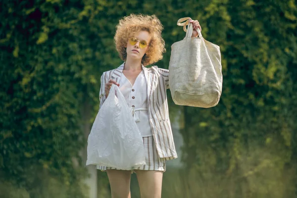 Zázvorová dívka drží eko tašku a plastixc tašku v nhands — Stock fotografie