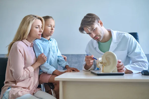 Audiologista mostrando o modelo de demonstração do sistema auditivo para seus pacientes — Fotografia de Stock