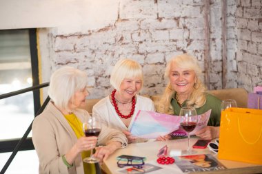 Üç olgun kadın masada oturuyor ve heyecanlı görünüyorlar.