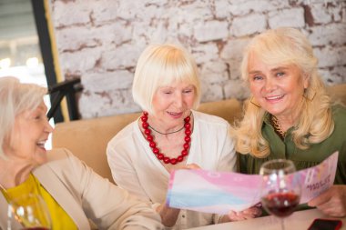 Üç olgun kadın masada oturuyor ve heyecanlı görünüyorlar.
