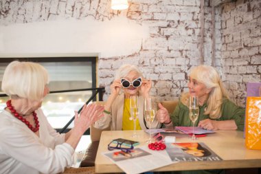 Üç kadın yeni güneş gözlüğü denerken iyi vakit geçiriyor.