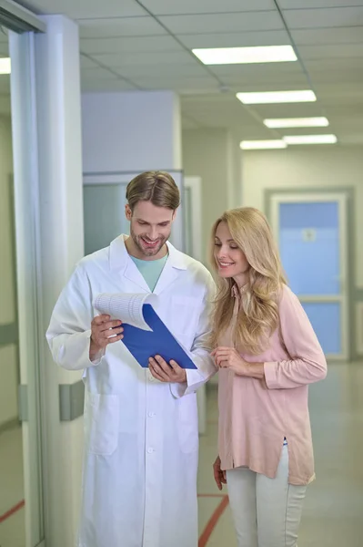 Médico sorridente e uma mulher alegre examinando um documento — Fotografia de Stock