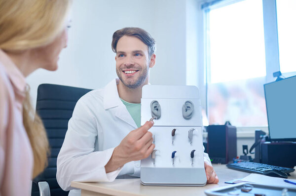 Дружелюбный доктор, предлагающий пациенту различные средства глухоты