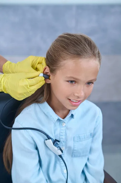 Guantes manos poniendo en prueba de audición para niña — Foto de Stock