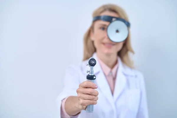 Woman in white coat with mirror and otoscope — Stock Photo, Image