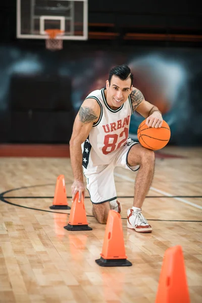Tatuerad man i vit shportswear spelar basket — Stockfoto