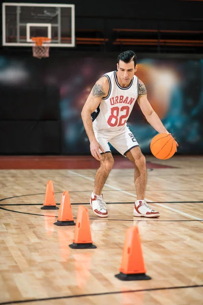 Tattoed man in white shportswear playing basket-ball — Stock Photo, Image