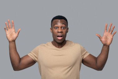 Koyu tenli genç adam şaşırmış ve şok olmuş görünüyor.