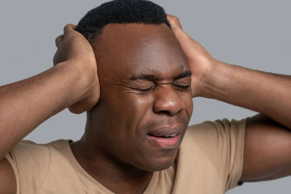 Чернокожий молодой человек закрывает уши и закрывает глаза. — стоковое фото