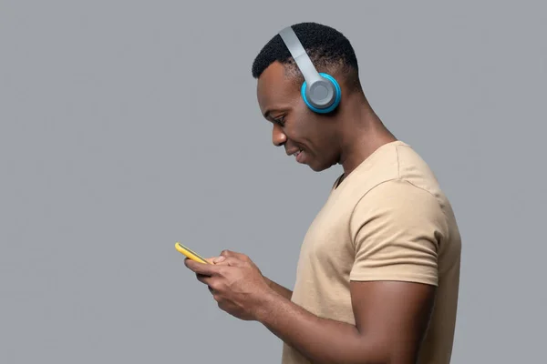 Pemuda berkulit gelap dengan headphone mendengarkan musik — Stok Foto