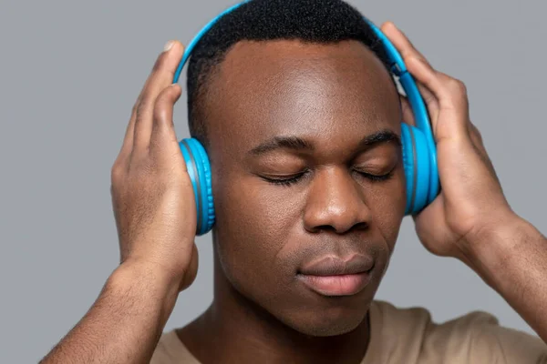 Joven de piel oscura con auriculares escuchando música — Foto de Stock