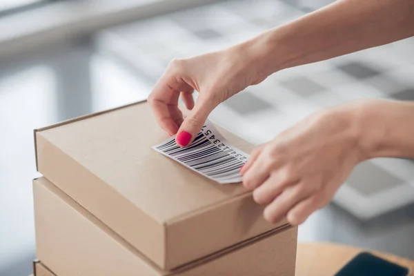 Woman employee preparing barcoded goods for shipping — Stock Photo, Image