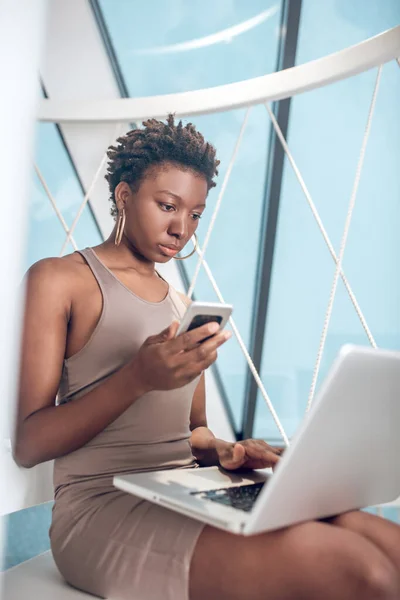 Femme avec smartphone et ordinateur portable dans un espace de bureau — Photo