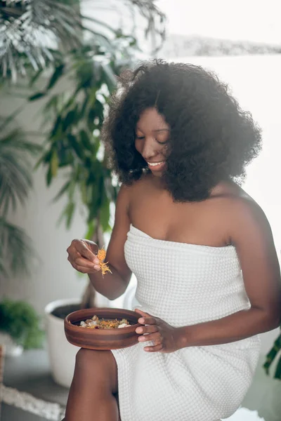 Темношкіра молода жінка з тарілкою з пелюсток — стокове фото