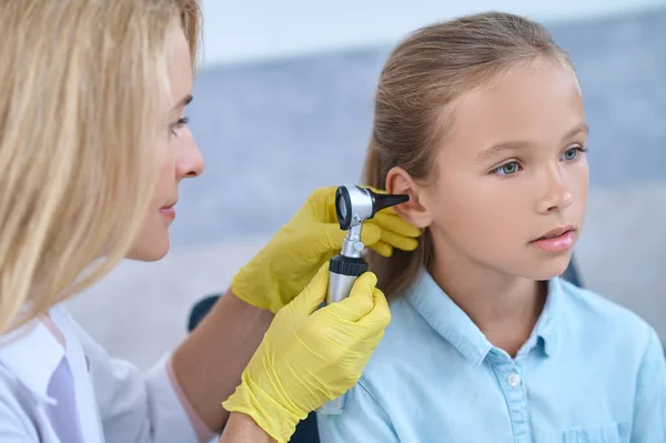 Otorinolaringoiatra con otoscopio vicino all'orecchio della bambina — Foto Stock