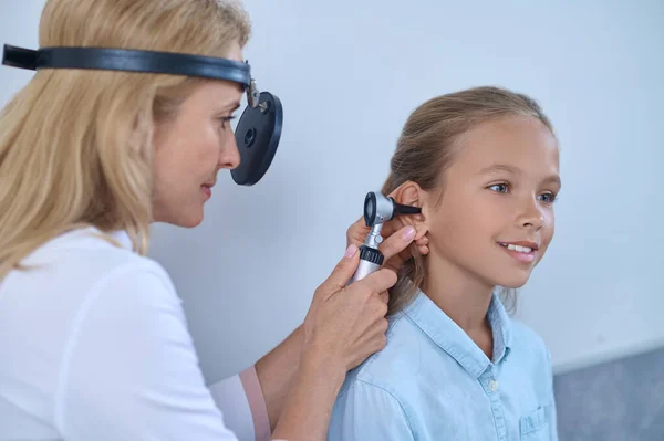 Médico experimentado insertando el auriscopio en el canal auditivo de los pacientes — Foto de Stock