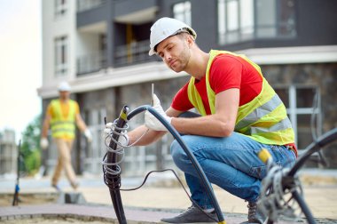 Pamuk eldiven takıp elektrik yükleyen konsantre yetenekli inşaat işçisi.