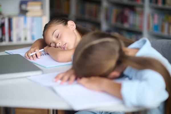 Linda chica con un bolígrafo y su amigo agotado dormitando juntos —  Fotos de Stock