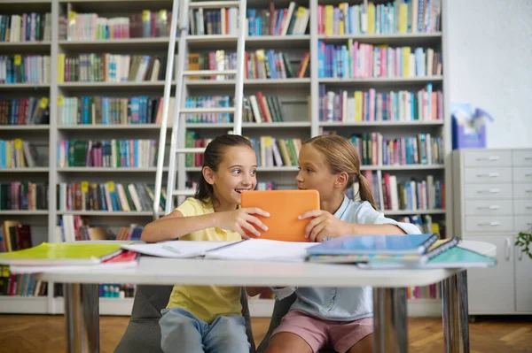 Écolière pleine d'entrain et son cher camarade de classe dans une bibliothèque publique — Photo