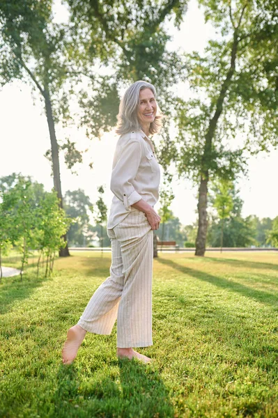 Радісна елегантна жінка стоїть босоніж на траві — стокове фото