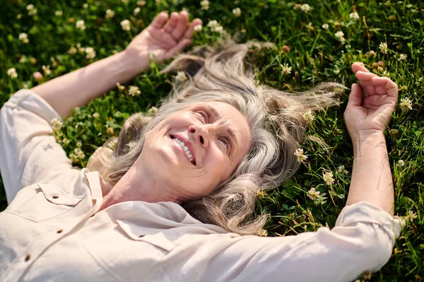 Щаслива жінка лежить на зеленому газоні — стокове фото