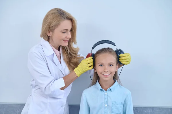 Lekarz przygotowujący młodego pacjenta do badania audiometrycznego — Zdjęcie stockowe