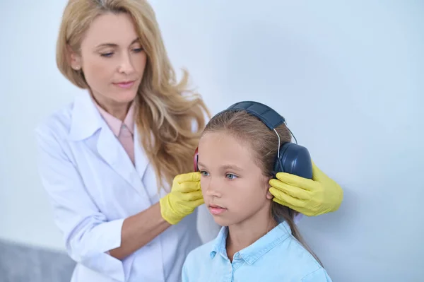 Konzentrierter Audiologe bereitet einen jungen Patienten auf einen audiometrischen Test vor — Stockfoto