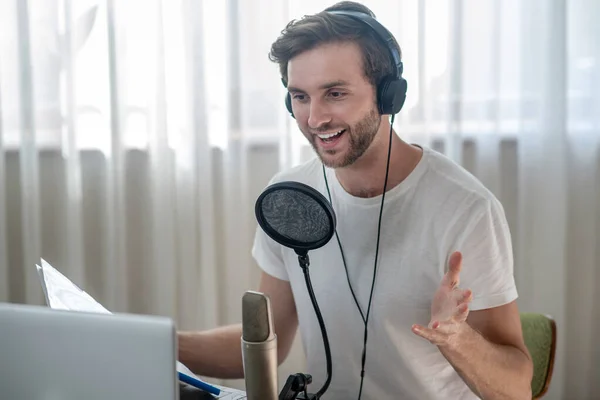 Young bearded man sitting in headphones and having an audio conference — Stock Photo, Image