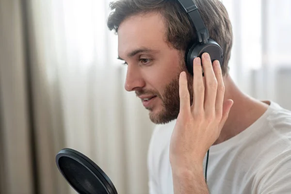 Uma foto de um homem com fones de ouvido pretos falando em microfone — Fotografia de Stock