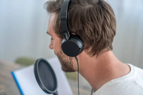 Una foto de un hombre con auriculares negros hablando en micrófono —  Fotos de Stock