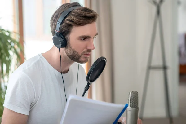 A young man speaking oin microphone and looking involved — Stock Photo, Image