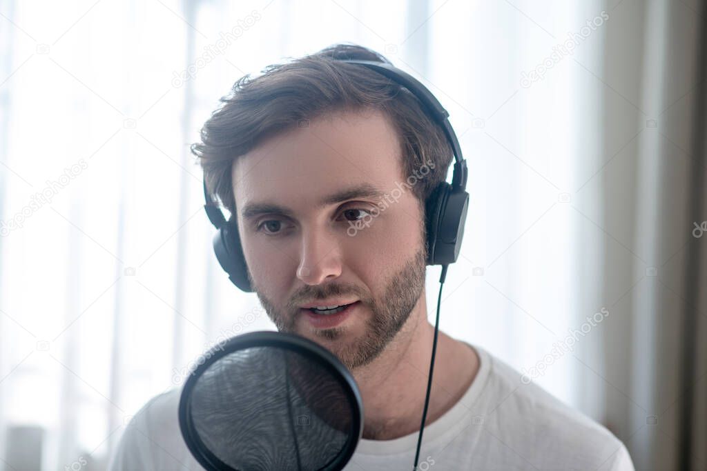 Young bearded man sitting in headphones and having an audio conference