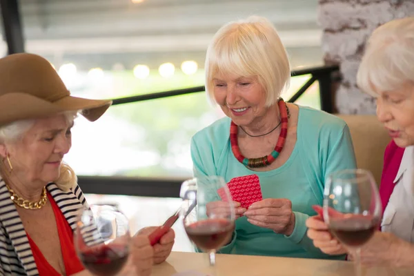 Старшие веселые женщины играют в карты и выглядят взволнованными — стоковое фото