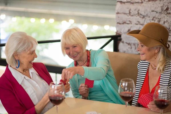 Старшие симпатичные веселые женщины, играющие в карты и с удовольствием выглядящие — стоковое фото