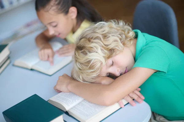 Flitig flicka och utmattad sömnig pojke på biblioteket — Stockfoto