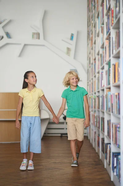 Two children impressed by a variety of books on the shelves — Stock Photo, Image