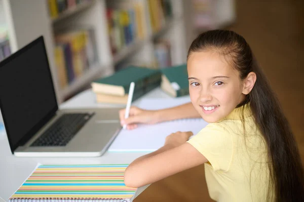 Zufriedene Schülerin macht sich Notizen in ihrem Notizbuch — Stockfoto