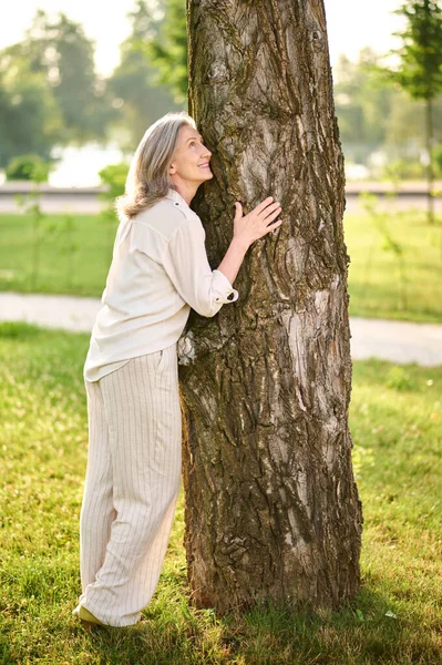 Vrouw leunend tegen boom in groen park — Stockfoto