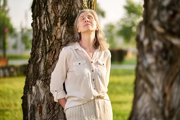 Розслаблена жінка з закритими очима біля дерева — стокове фото