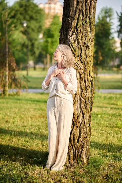 Vrouw met gesloten ogen leunend op boom — Stockfoto