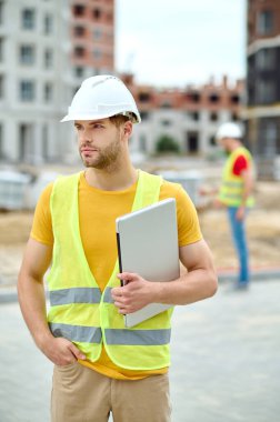 Koruyucu miğferli çekici mühendis başka tarafa bakıyor.