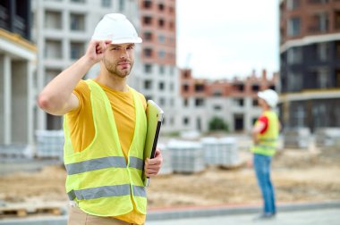 İnşaat alanında duran baret içindeki sakin mühendis.