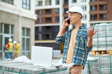 Bilgisayarının önünde duran akıllı telefonlu hayret verici mühendis.