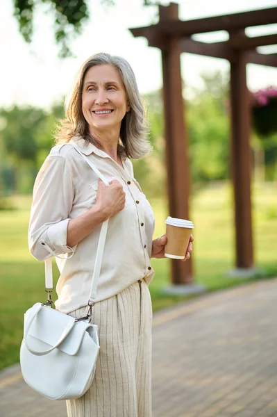 Счастливая элегантная женщина с кофе на прогулке — стоковое фото