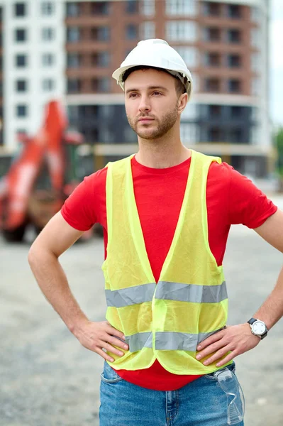Worker in a safety vest and a helmet standing outdoors — Stock Photo, Image