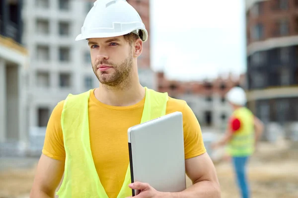 Bonito trabalhador de construção focado em headwear olhando para frente — Fotografia de Stock